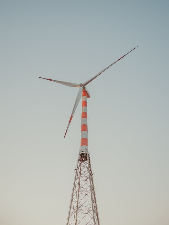 A modern wind turbine with red stripes stands tall against a clear sky, symbolizing sustainable energy.